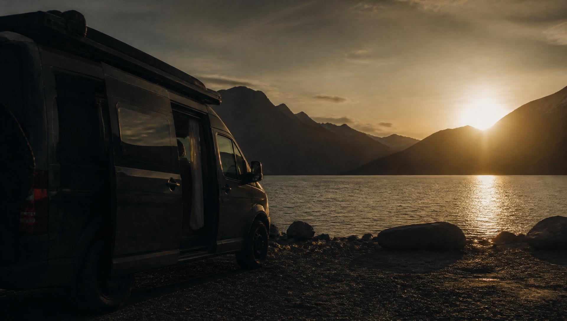 Campervan parked beside a remote lake at sunset