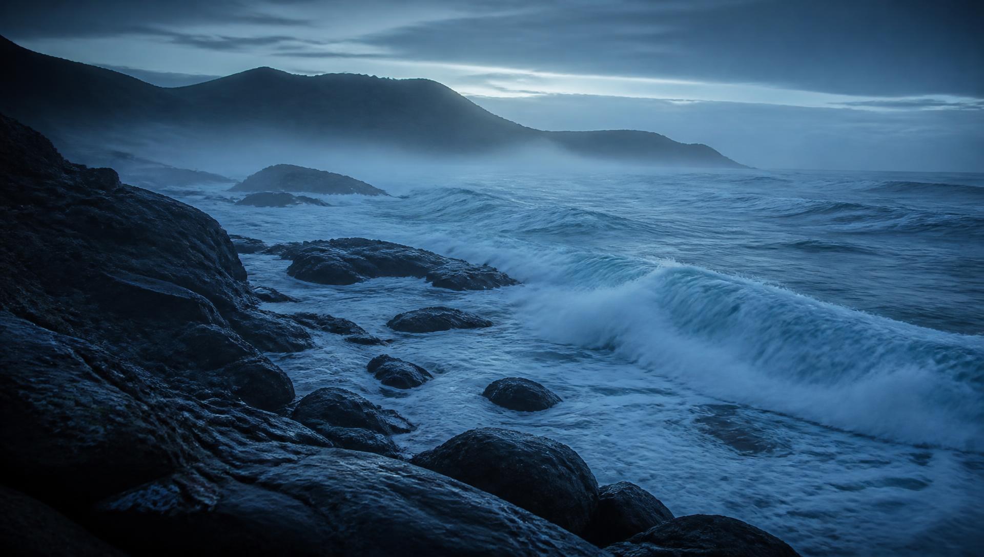 Swell breaking over dark coastal rocks at first light